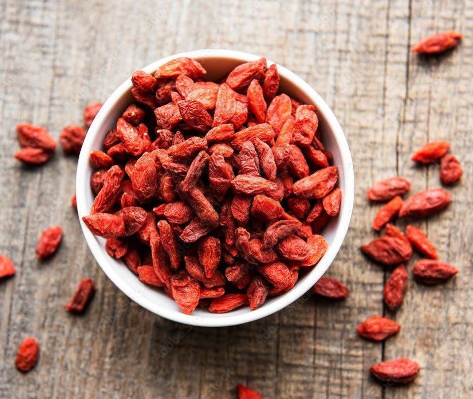 primo piano di ciotola bianca che contiene bacche di goji, foto dall'alto