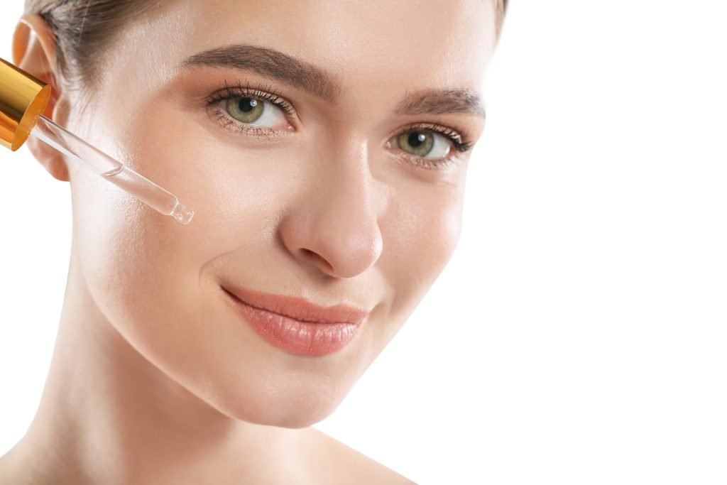 RAGAZZA CON CONTAGOCCE POSATO SULLA GUANCIA che applica siero per esfoliazione viso 