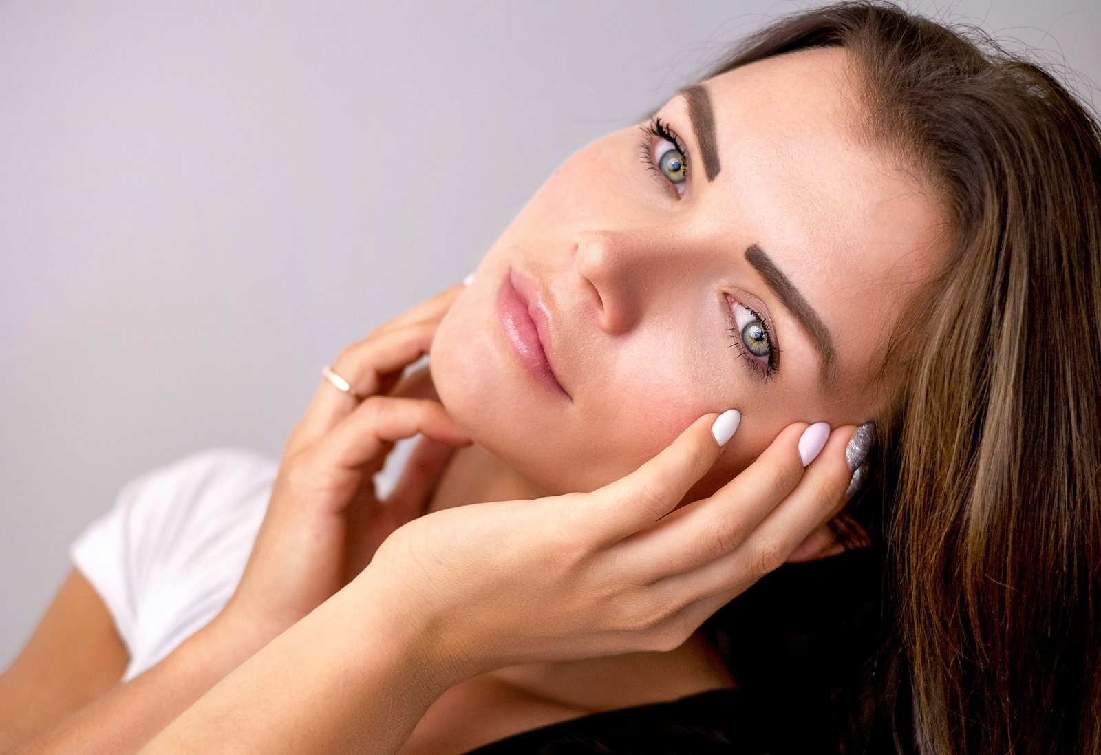 CONCETTO Integratori antiossidanti e antiage, cura della pelle: bella ragazza con pelle perfetta si accarezza viso con le mani 