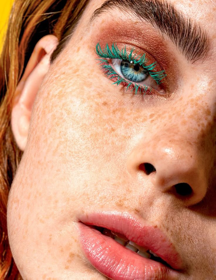 CLOSE UP SU VISO DI RAGAZZA CON OCCHI VERDI CHE INDOSSA MASCARA COLORATI