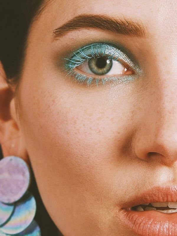CLOSE UP SU VISO DI RAGAZZA CON OCCHI VERDI CHE INDOSSA MASCARA COLORATI