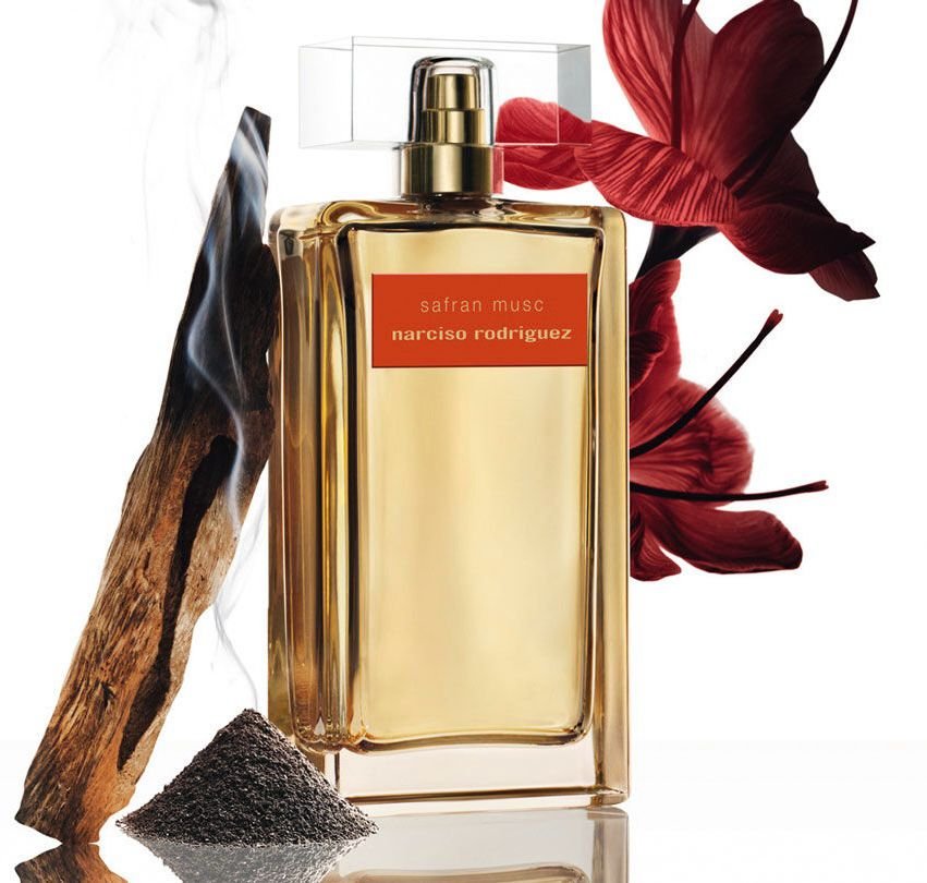 Safran Musc Eau de Parfum Intense – Narciso Rodriguez fotografato con dell'incenso e dei fiori rossi accanto 