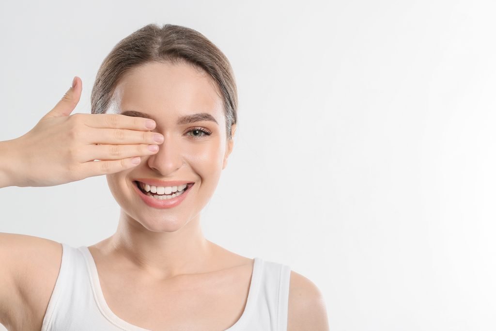 ragazza giovane che sorride e si copre occhio con la mano