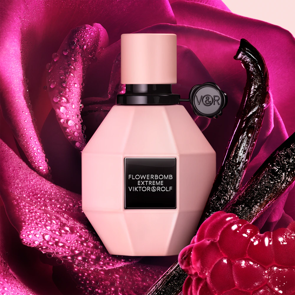 Profumi donna novità 2025 Flowerbomb Extrême – Viktor & Rolf fotografato su una stoffa di raso color granata umida di gocce e con bastoncini di vaniglia e ciligie accanto 