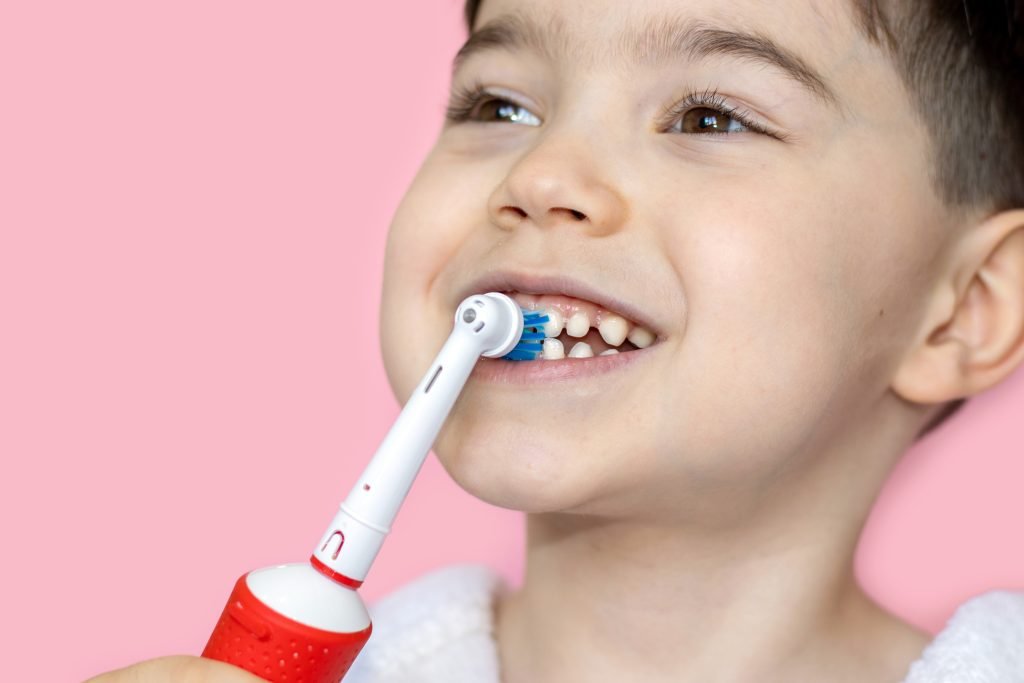 bambino in primo piano che si lava i denti con lo spazzolino elettrico 