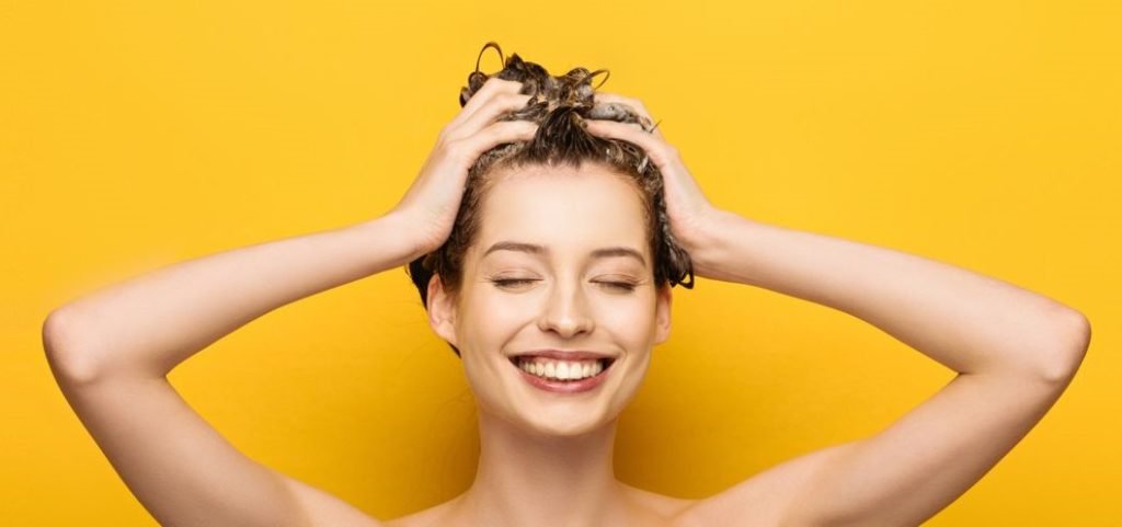 primo piano di donna che fa scrub capelli massaggiando con le dita 