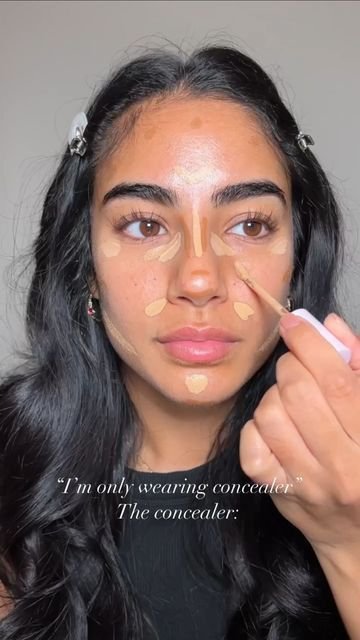 ragazza mora con capelli lunghi che usa il correttore per realizzare il makeup di una base viso naturale