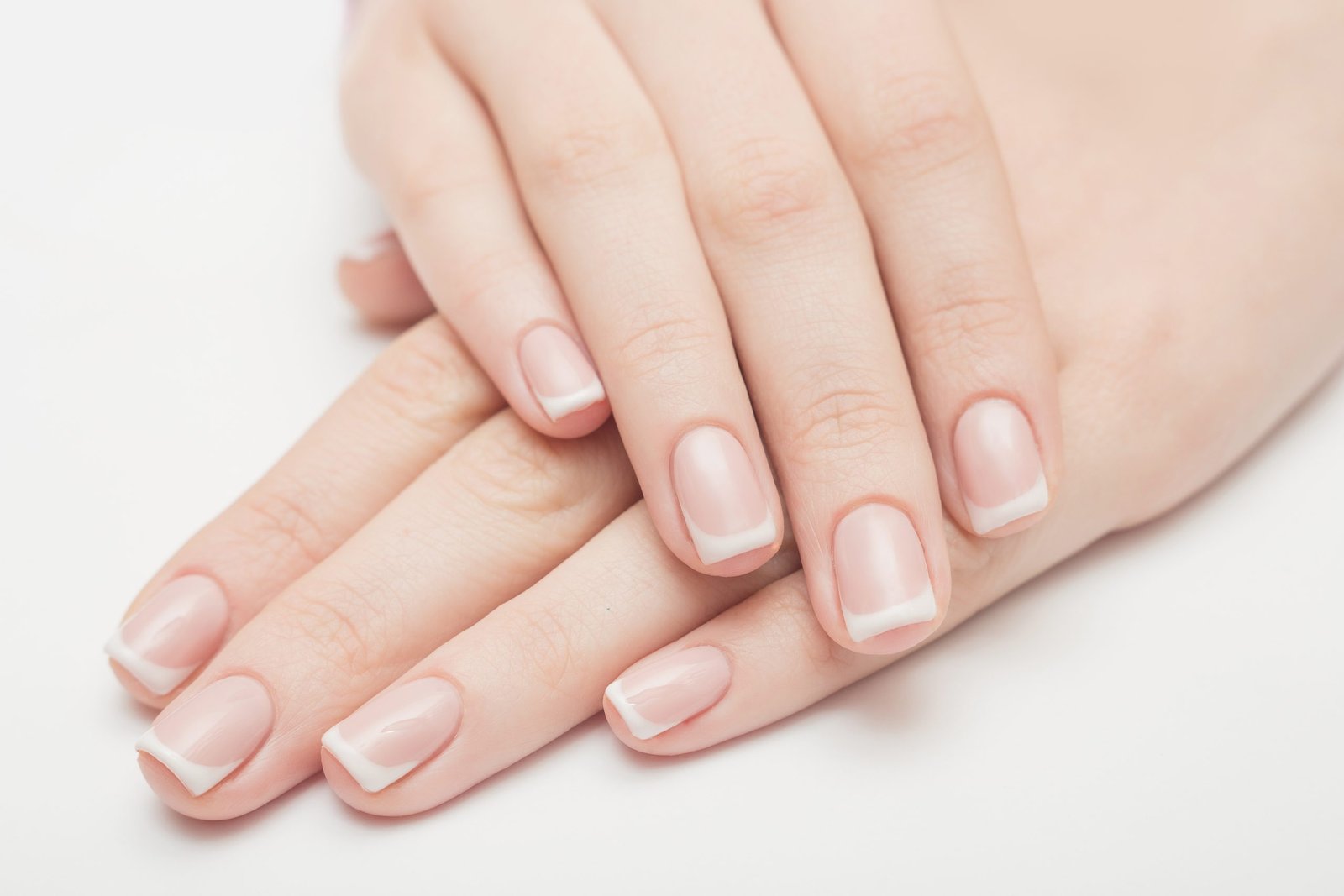 primo piano di mani curate e sane con manicure delicata stile french. concetto di mani e carenze nutrizionali e di unghie e carenze nutrizionali