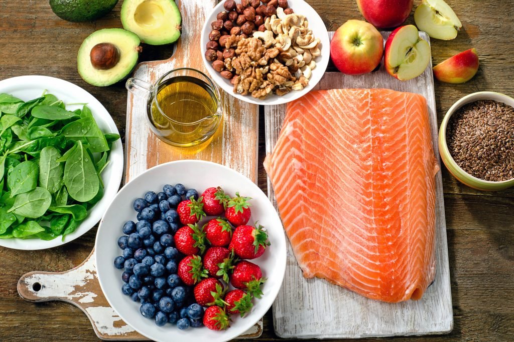 primo piano di tavola imbandita con alimenti sani : salmone, avocado, frutti di bosco, verdure e frutta 