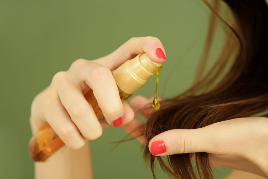 primo piano su mano che eroga un siero o olio sui capelli 