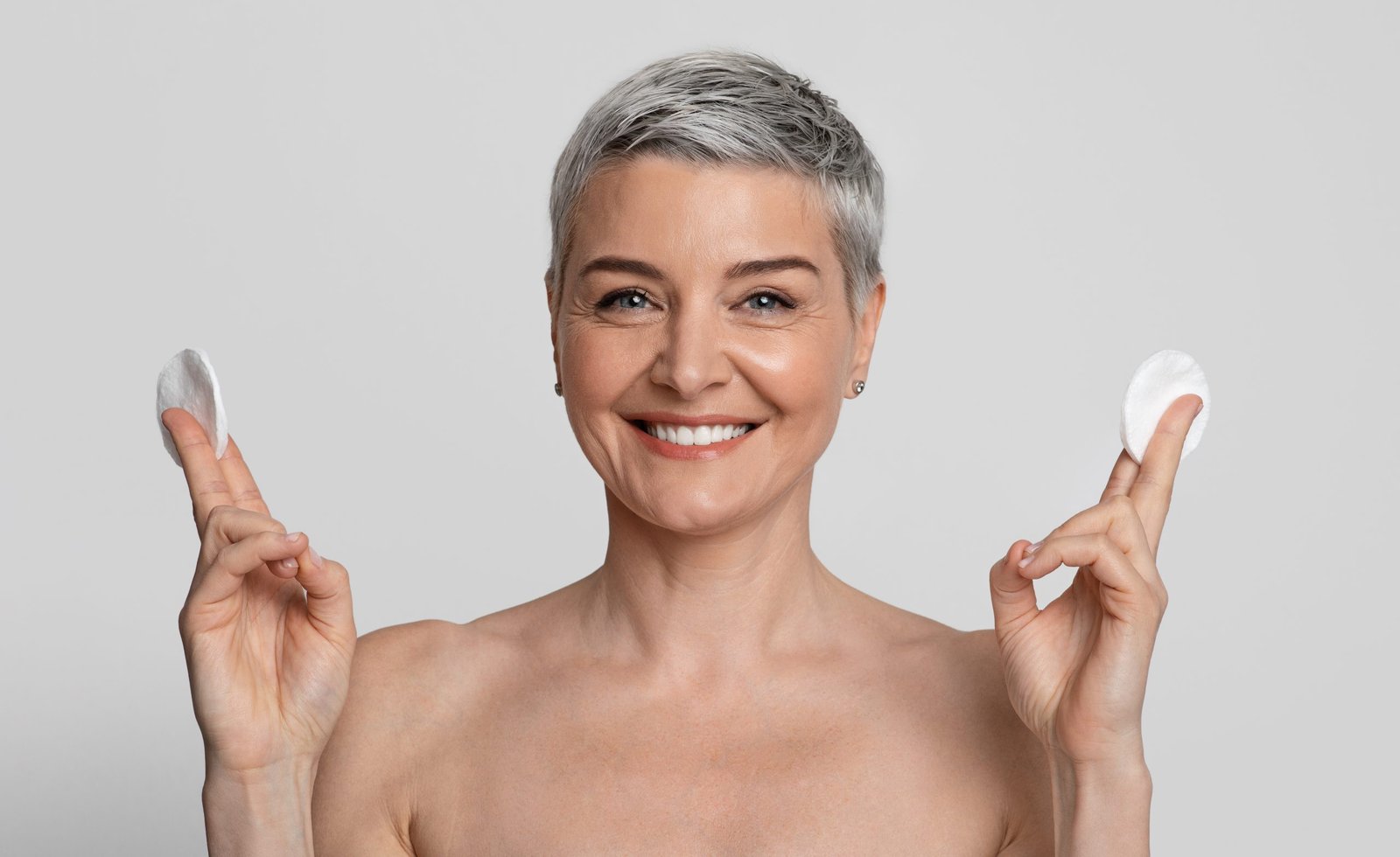 Concetto di skincare routine pelle matura Attraente donna di mezza età in posa con dischetti di cotone in mano