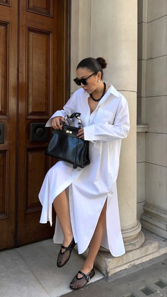 Donna asiatica che tiene in mano borsa nera e indossa chemisier bianco e ballerine in rete economiche 