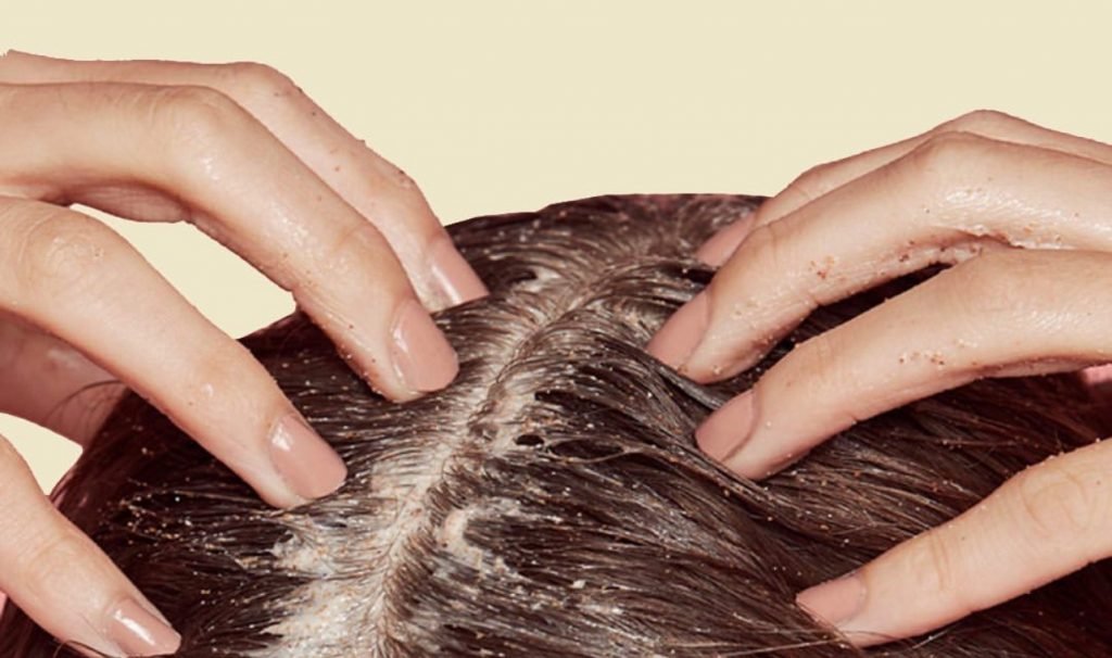 primo piano su mani che applicano lo scrub per il cuoio capelluto 