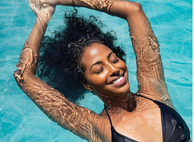 ragazza afro in piscina con occhi chiusi si gode relax