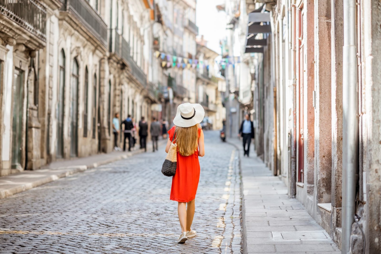 Giovane turista in abito rosso che cammina per le strade del centro storico di Porto, Portogallo