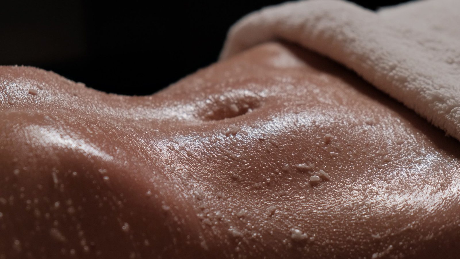 Massaggio scrub corpo con addome di una ragazza in primo piano. Concetto lo scrub toglie l'abbronzatura