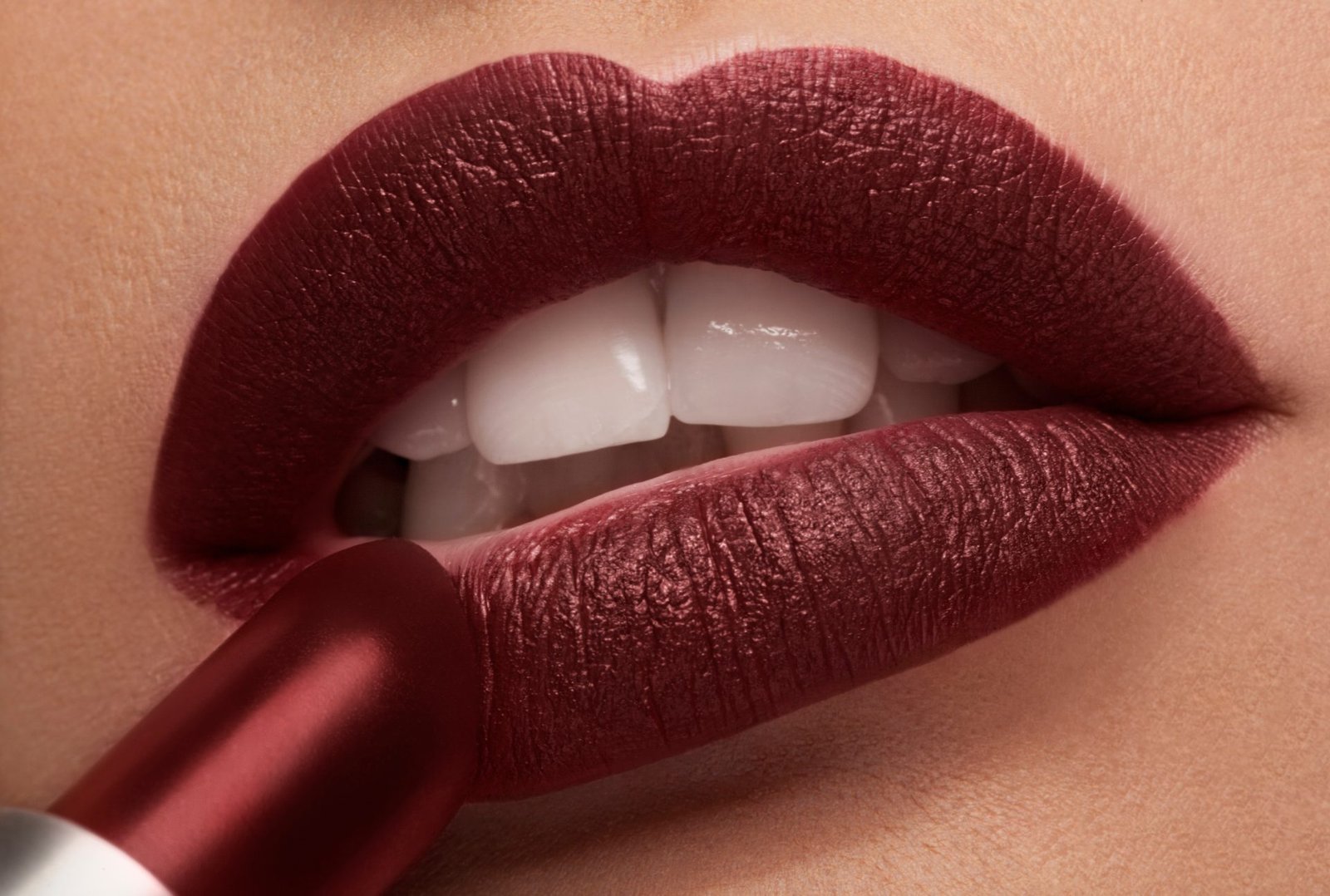 Applicazione del rossetto rosso sulle labbra in una foto ravvicinata con illuminazione da studio. ROSETTI OPACHI ECONOMICI