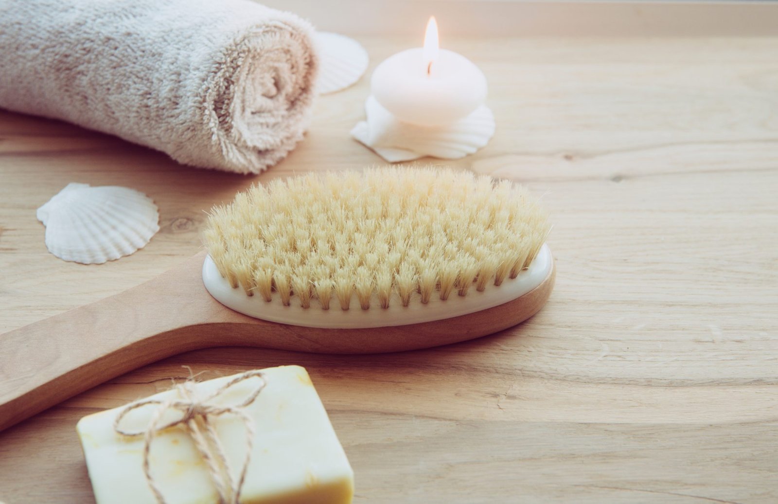 primo piano di spazzola di legno per la spazzolatura a secco, sapone e asciugamano arrotolato . Atmosfera rilassante in un bagno 