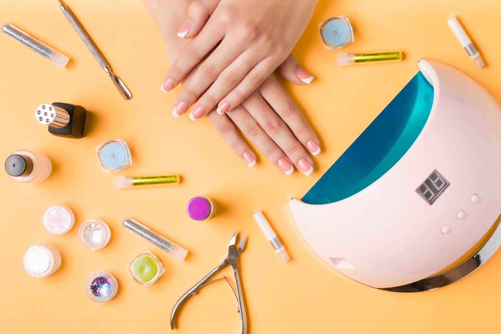 Composizione per la cura delle unghie, mani femminili giovani, manicure francese, smalto in gel tpo e dmta free, lampada per unghie e attrezzatura per la cura delle unghie. Foto in posizione orizzontale.