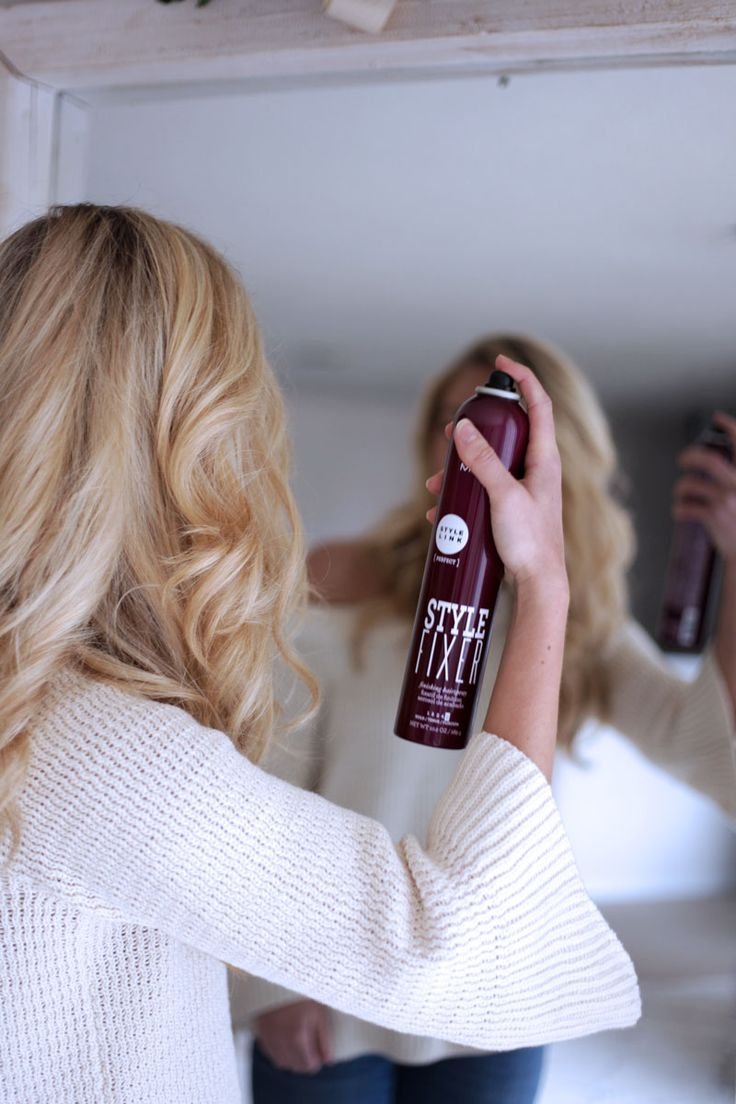 ragazza che si spruzza sui capelli la lacca per fisSARLI
