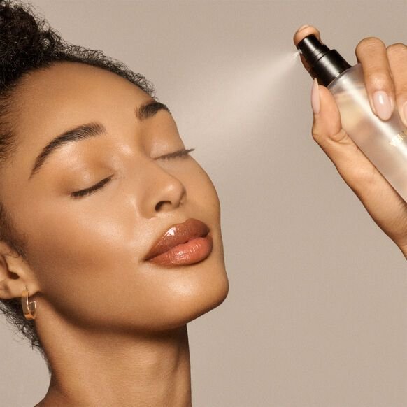 ragazza che si spruzza sul viso uno spray fissante makeup . Concetto fissatore trucco spray come si usa