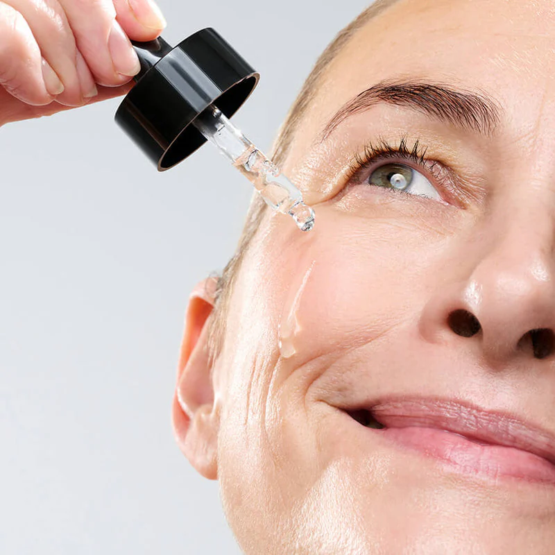 primo piano di donna matura che applica un siero viso 