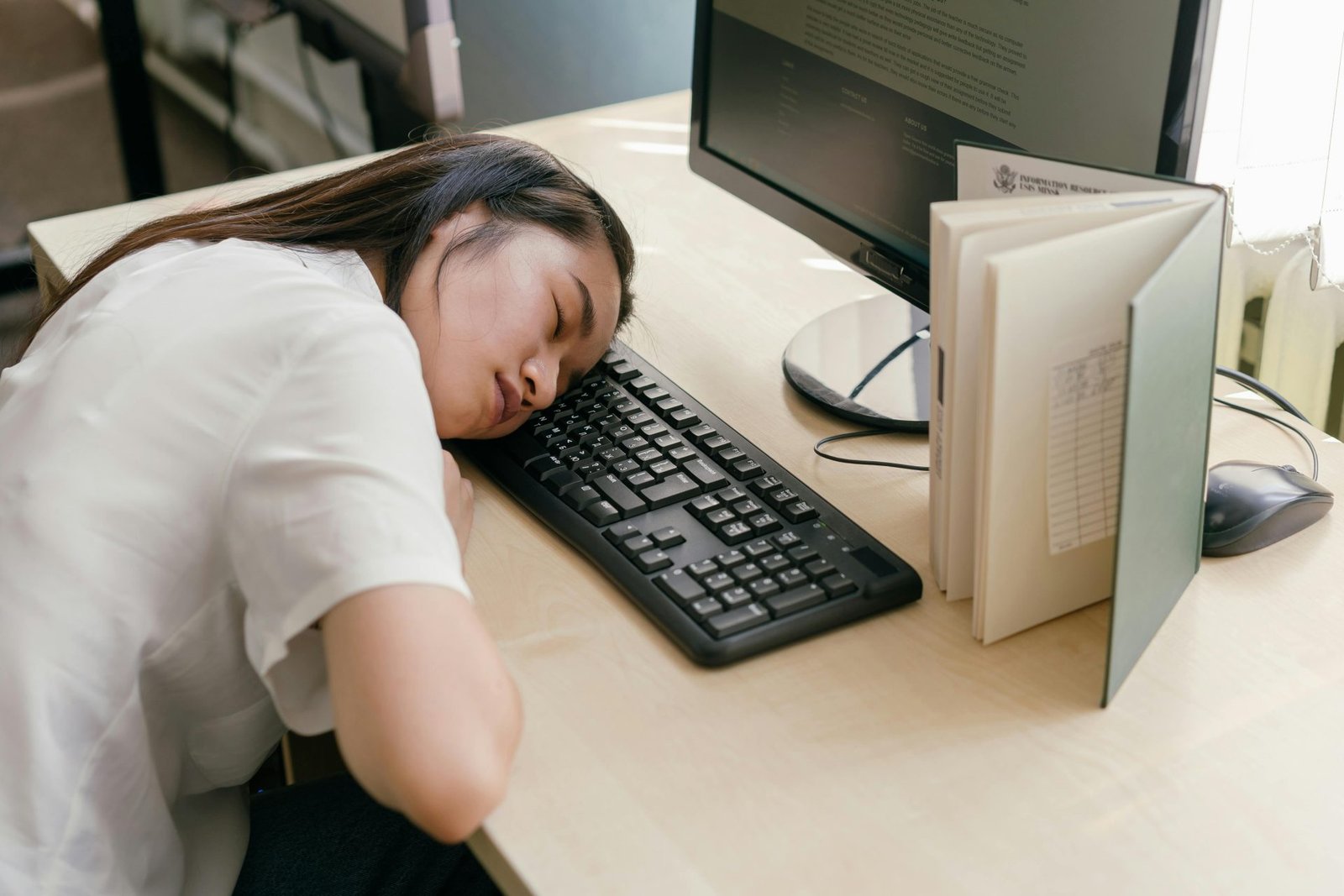 donna asiatica posa la testa sulla tastiera del pc sulla scrivania per riposare evidentemnte stanca e stressata - concetto Dormire poco rischi