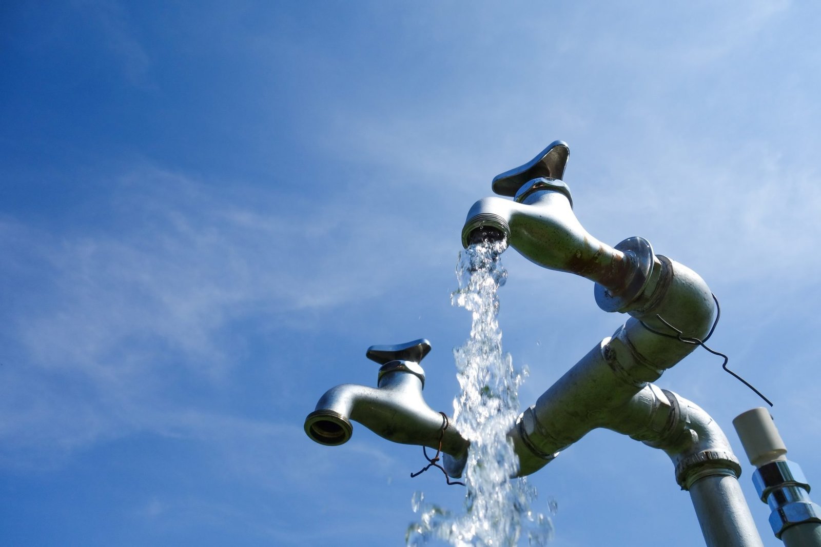 concetto: Bere acqua dal rubinetto fa male? Rubinetto in ambiente esterno con acqua che scorre