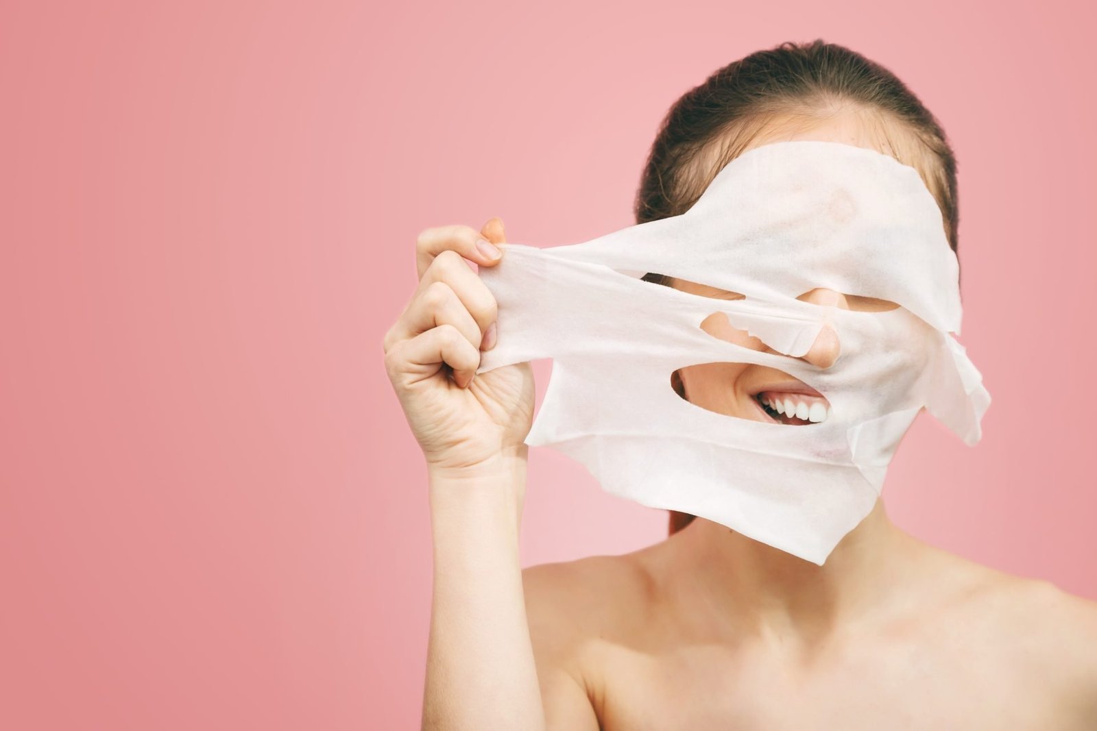 Ritratto di una bella ragazza sorridente che rimuove una maschera bianca dalla pelle sana e fresca- CONCETTO LE MASCHERE IN TESSUTO FUNZIONANO