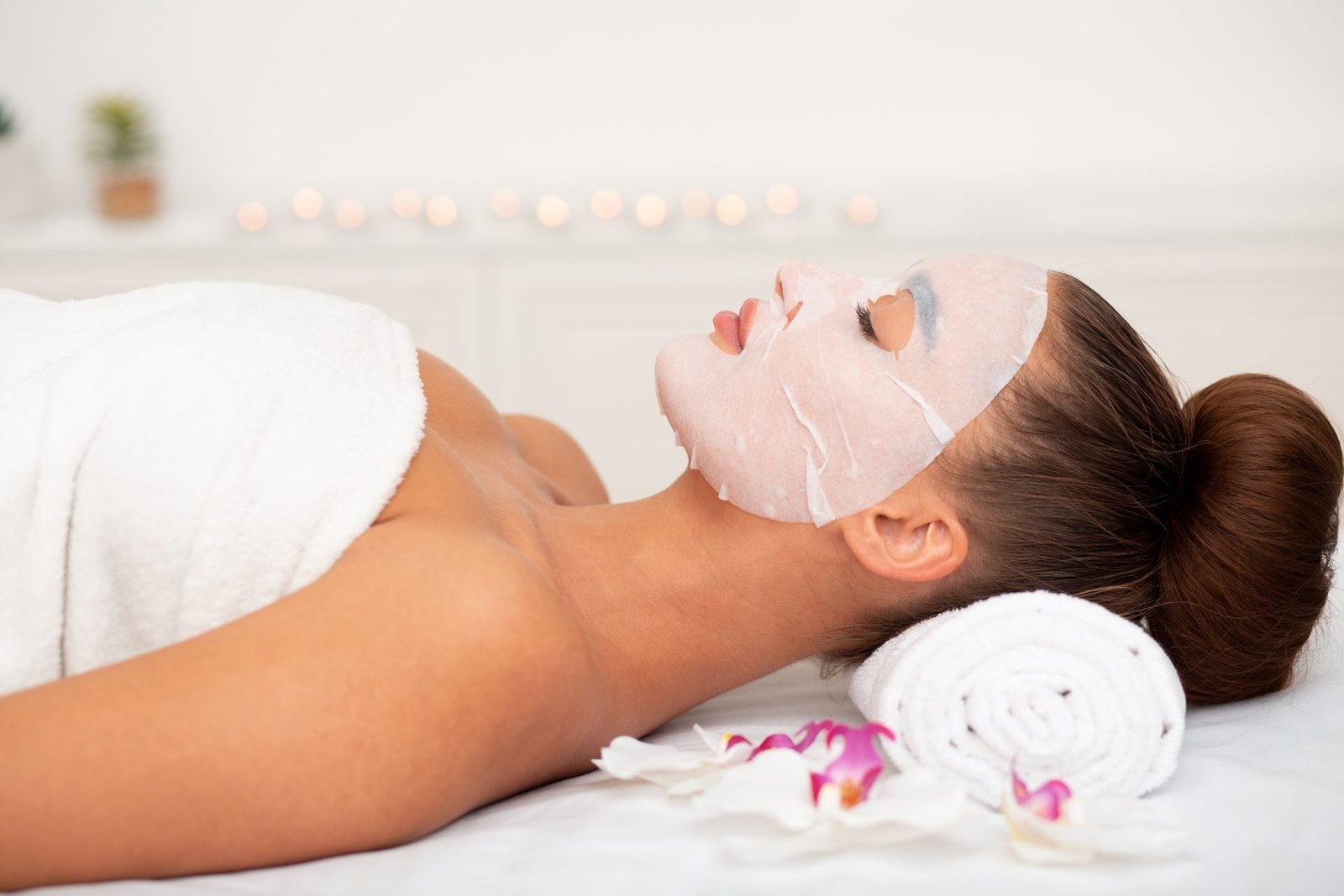 Donna con maschera di cotone in un salone di bellezza, che si rilassa dopo le procedure di cosmetologia, vista laterale- CONCETTO MASCHERE IN TESSUTO FUNZIONANO