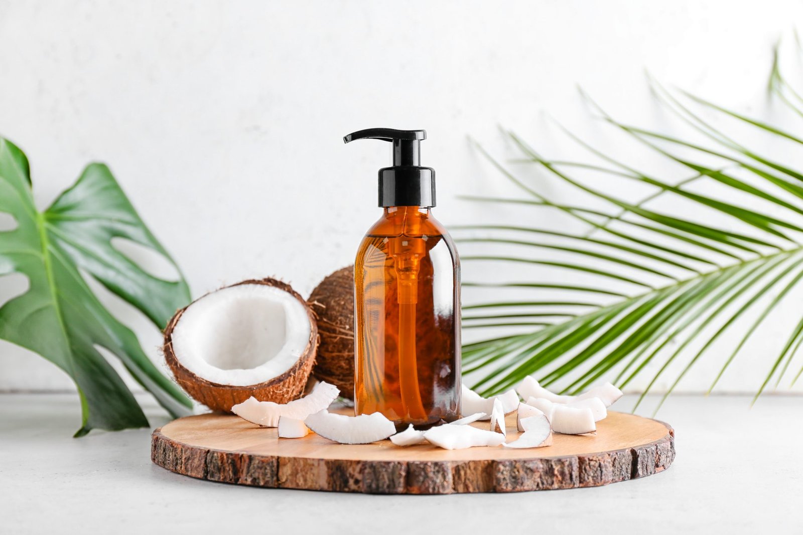 Composizione con bottiglia di olio di cocco su sfondo chiaro - concetto olio di cocco come usarlo
