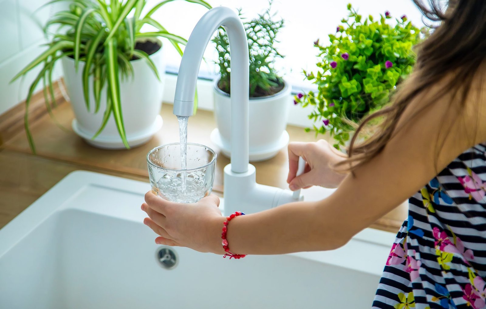 Bambini che prendono un bicchiere d'acqua dal rubinetto. Messa a fuoco selettiva. Bambino