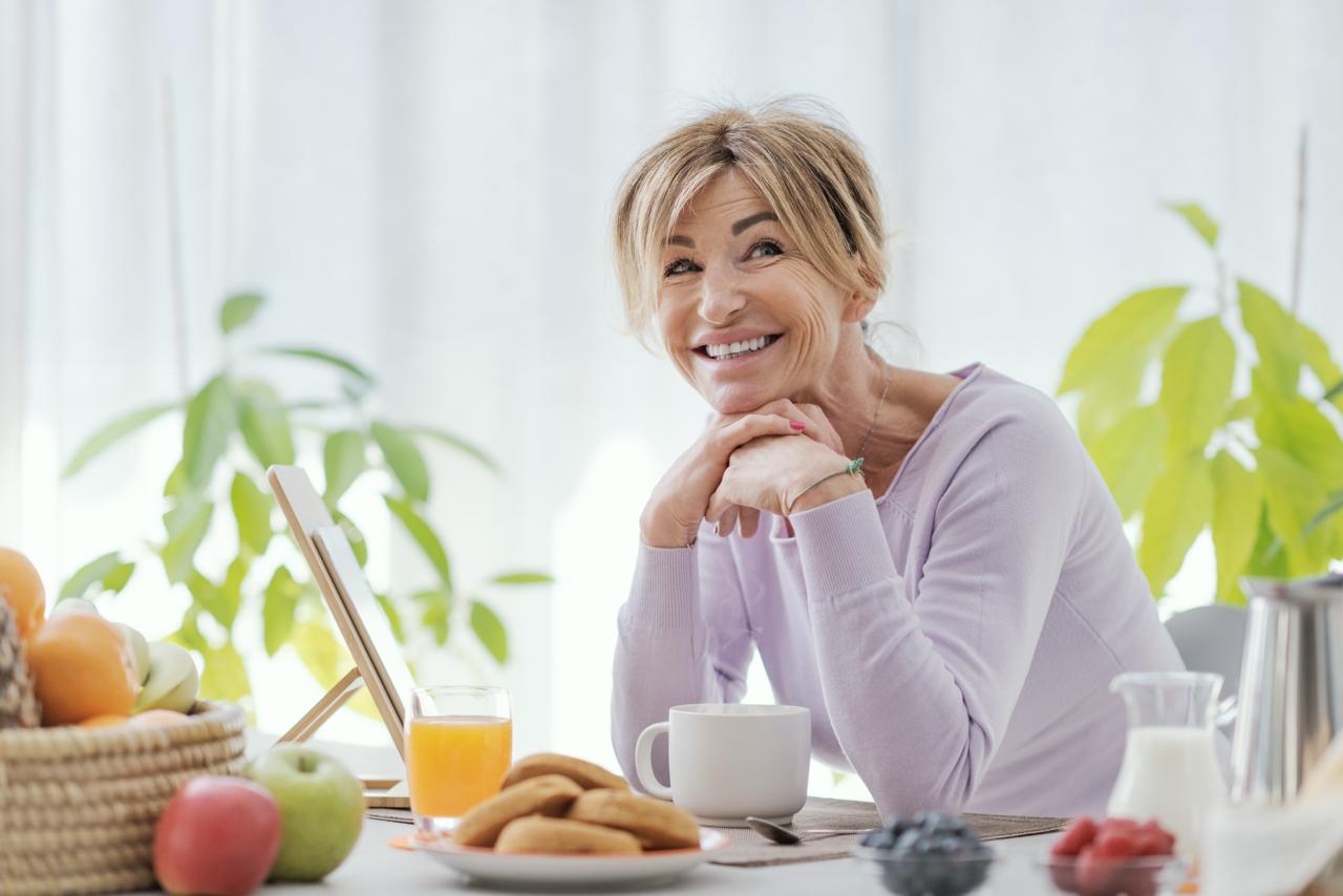IANO COLAZIONE IDEALE IN MENOPAUSA. Donna matura che fa colazione in relax a casa