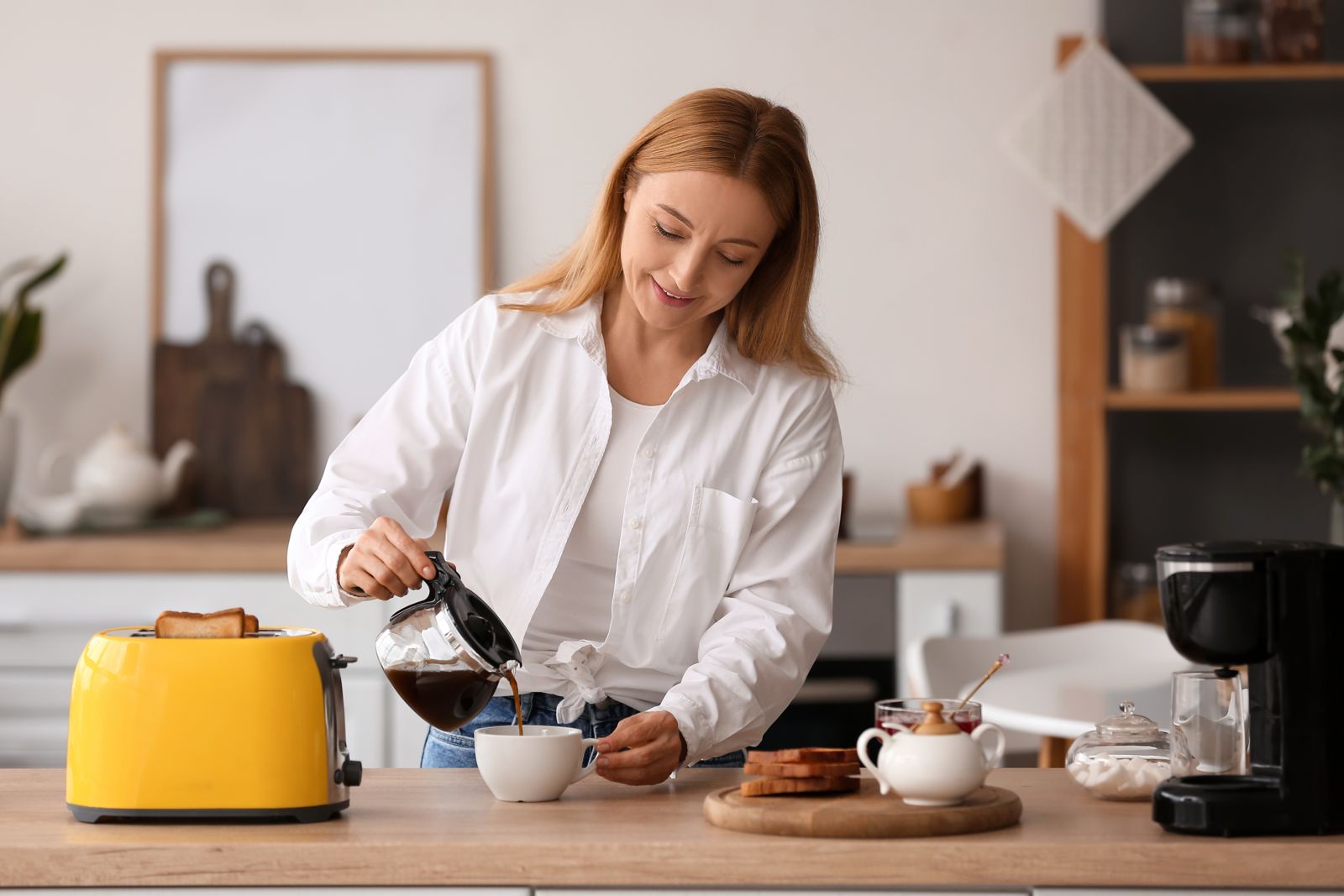 Donna matura che prepara gustosi toast e beve caffè in cucina- CONCETTO DI COLAZIONE IDEALE IN MENOPAUSA