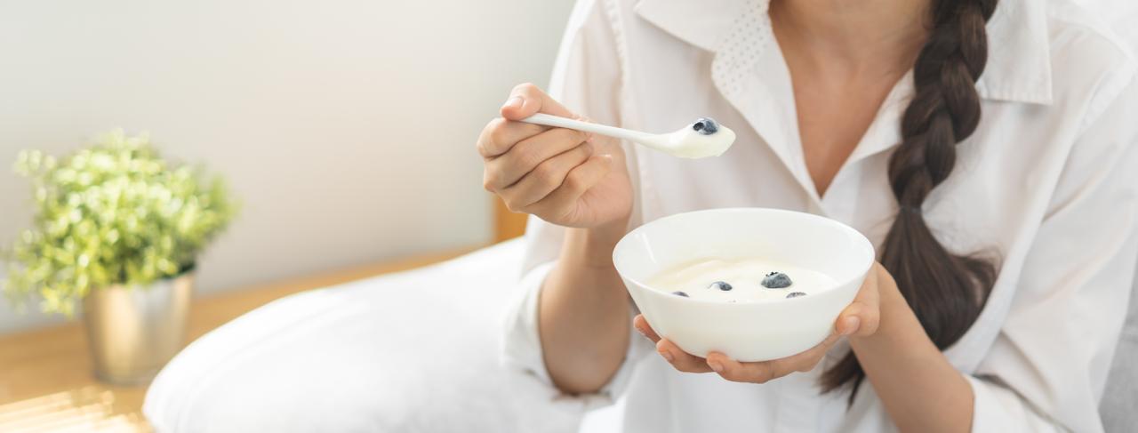 Stile di vita sano, cibo sano donna mangia un gustoso yogurt biologico fresco, latticini in una ciotola, pasto per la colazione a casa. Spuntino gustoso, dieta nutriente, delizioso yogurt naturale. COLAZIONE IDEALE IN MENOPAUSA