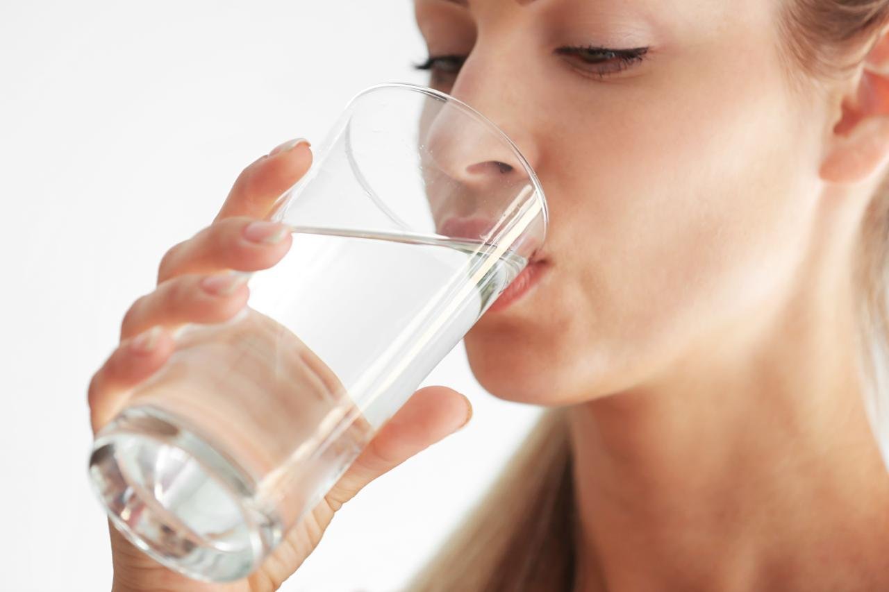 come non ingrassare durante le feste. importanza di bere abbastanza. donna in primo piano che beve bicchiere dacqua 
