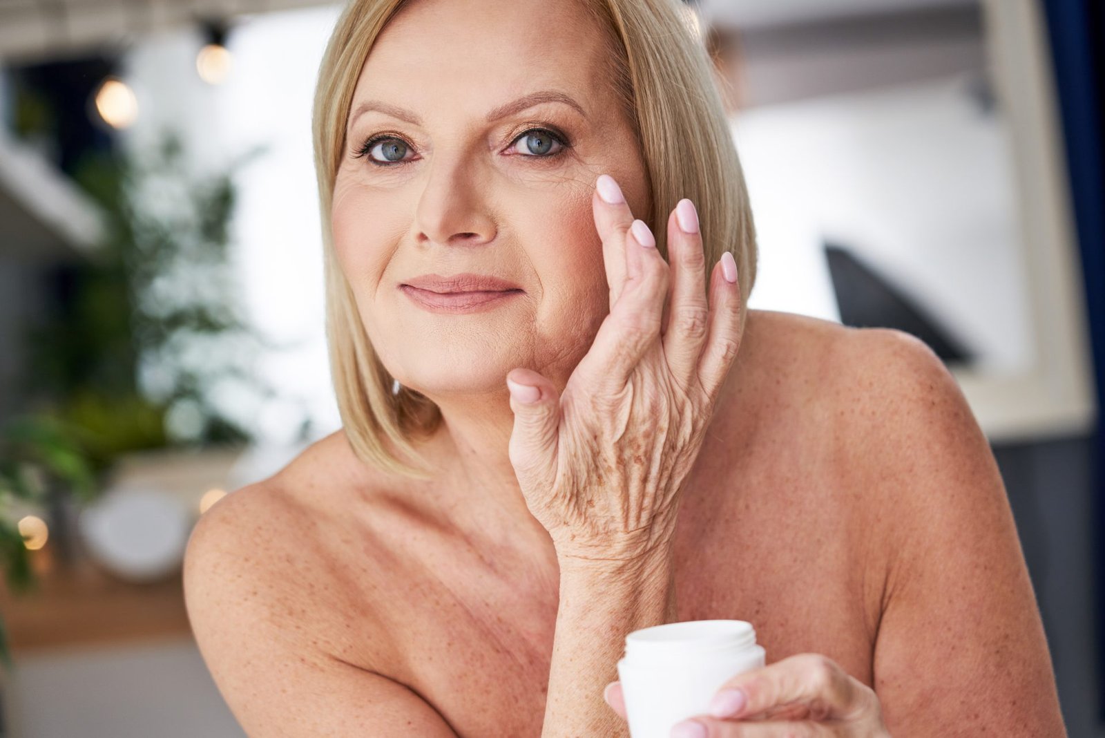 donna mezza età che esegue la skincare routine pelle matura nel suo bagno 
