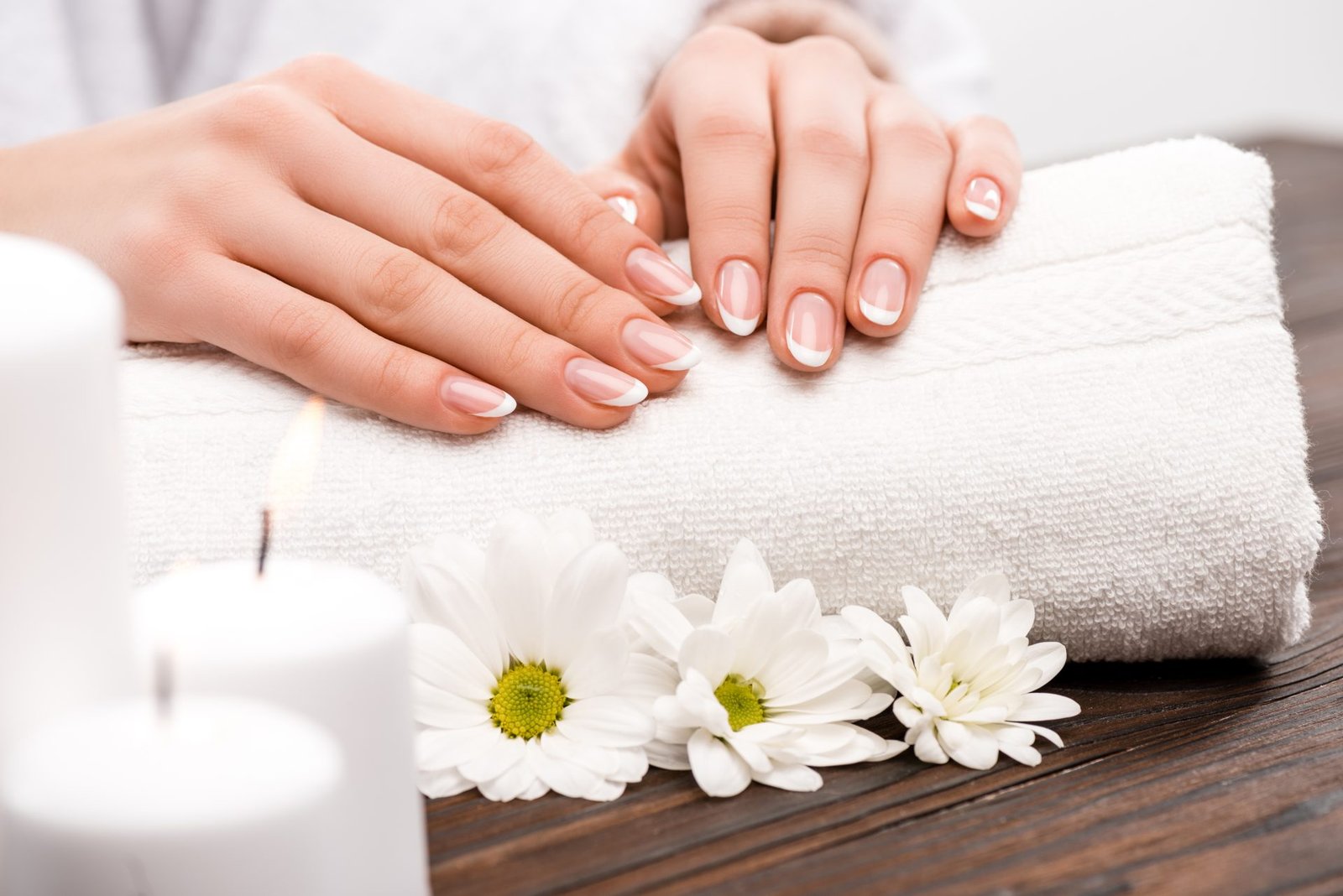 primo piano di mani curate su cuscino da manicure con fiori: concetto di Come fare una perfetta manicure fai da te su unghie naturali