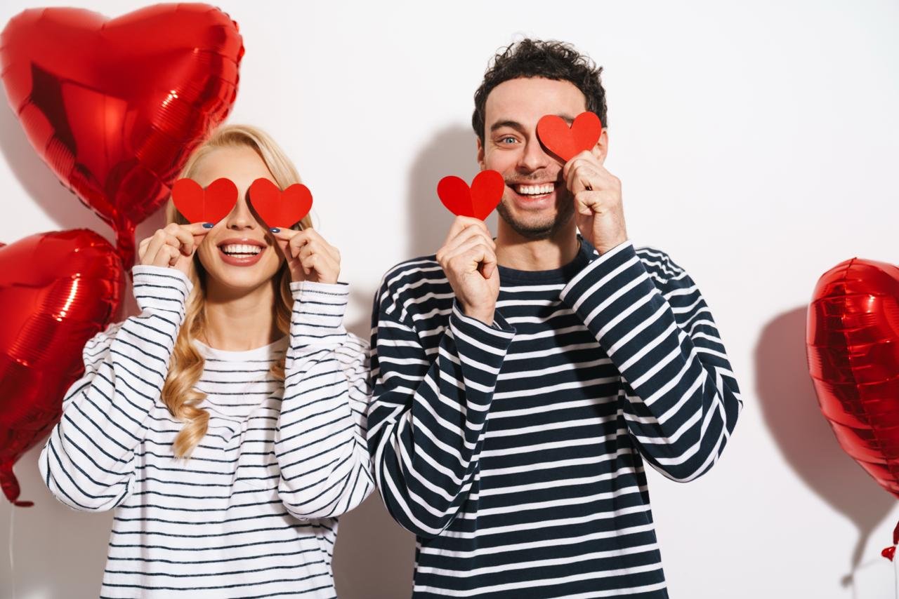 COPPIA vestita coordinata in maglia a righe gioca con dei cuori per festeggiare san valentino. Tema san valentino regali originali