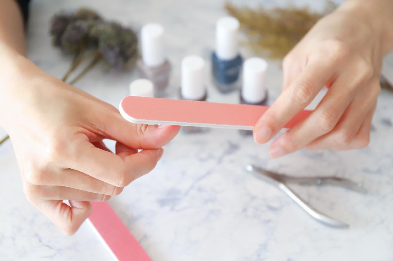 PRIMO PIANO DI MANI DI DONNA CHE LIMA UNGHIE: CONCETTO DI Come fare una perfetta manicure fai da te su unghie naturali