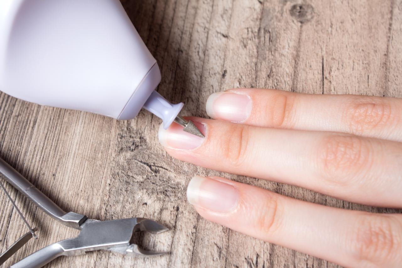  PRIMO PIANO DI MANO DI DONNA CHE FA LA MANICURE CON LA FRESA : CONCETTO DI Come fare una perfetta manicure fai da te su unghie naturali