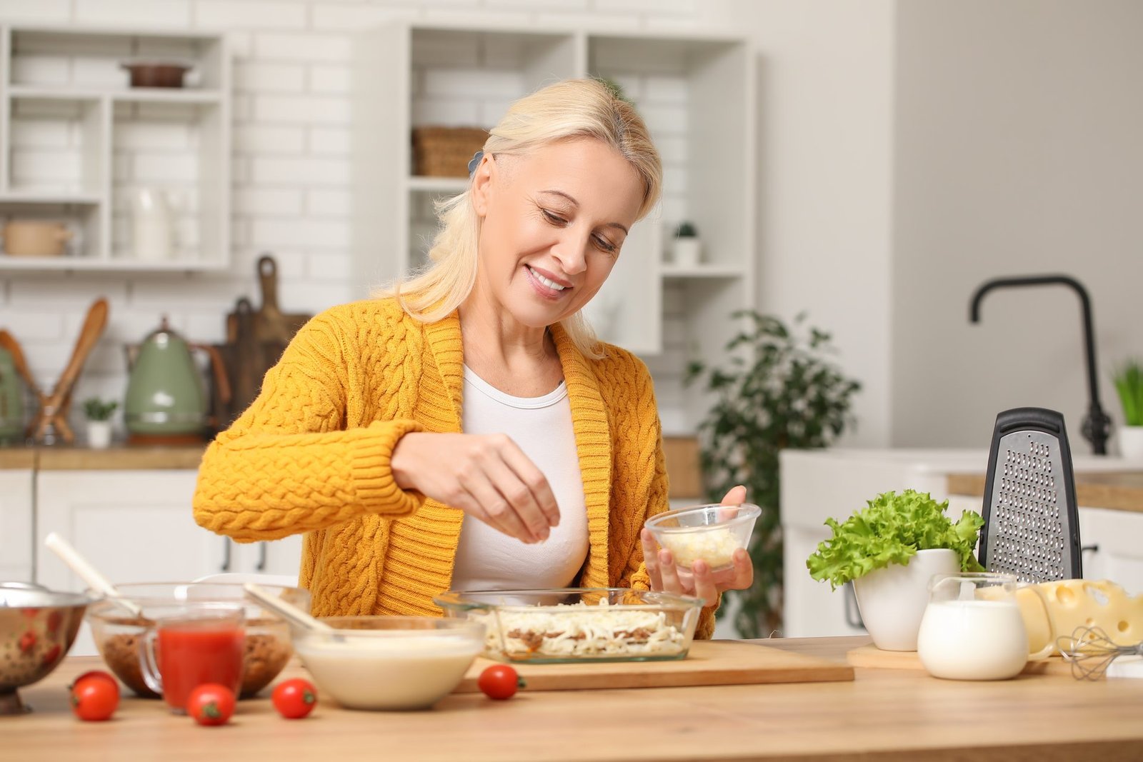 concetto quante proteine al giorno dopo i 50 anni. donna matura che PREPARA CIBO nella sua cucina