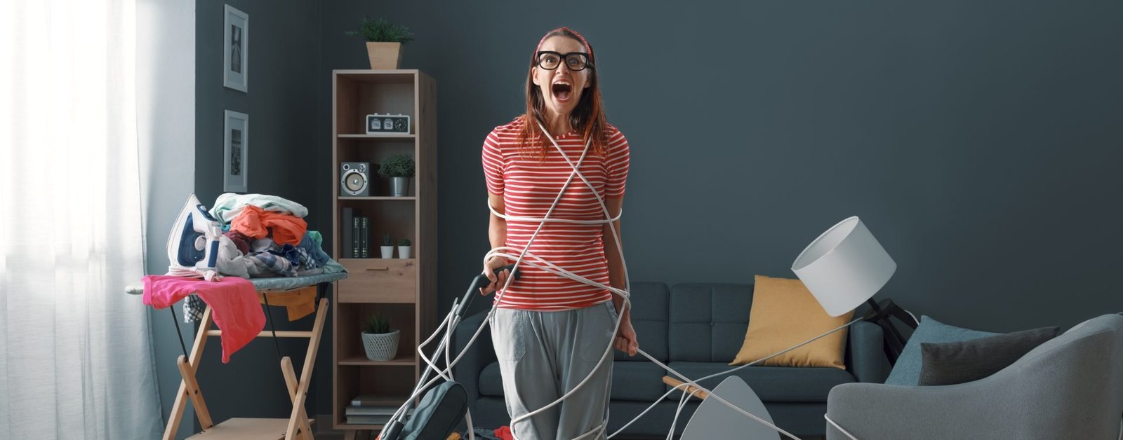 Casalinga frustrata che svolge le faccende domestiche a casa: è avvolta nei cavi, urla e pulisce una stanza in disordine- concetto di decluttering di primavera 