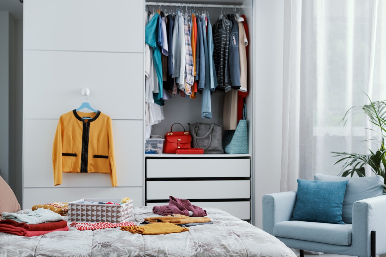 decluttering di primavera con vestiti nell'armadio e sul letto, interno della camera da letto