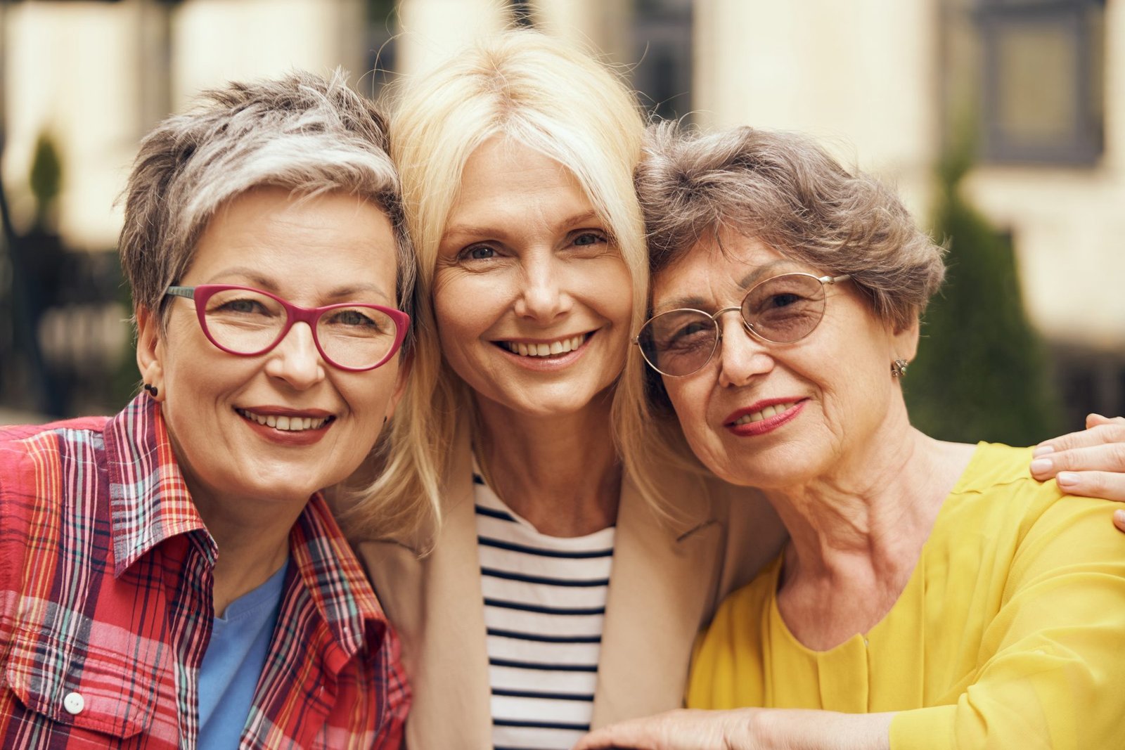 Donne di mezza età felici si abbracciano e guardano in camera in una strada cittadina. Amicizia femminile. concetto di come socializzare dopo i 50 anni