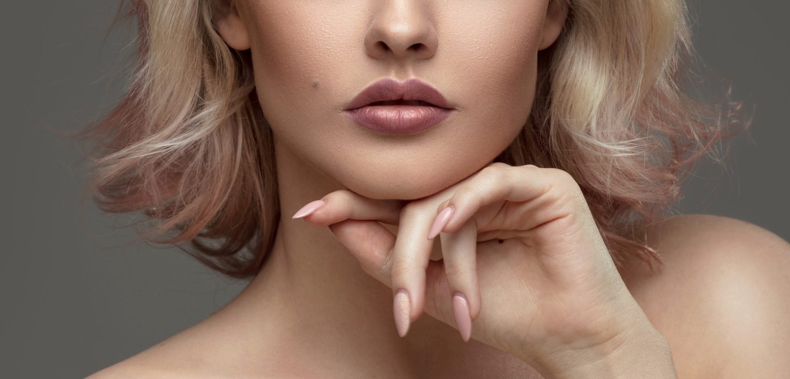 Ritratto ravvicinato di una donna. Bella ragazza con capelli biondi e trucco glamour. Labbra carnose e naturali. Unghie lunghe. Tema come far durare lo smto a lungo