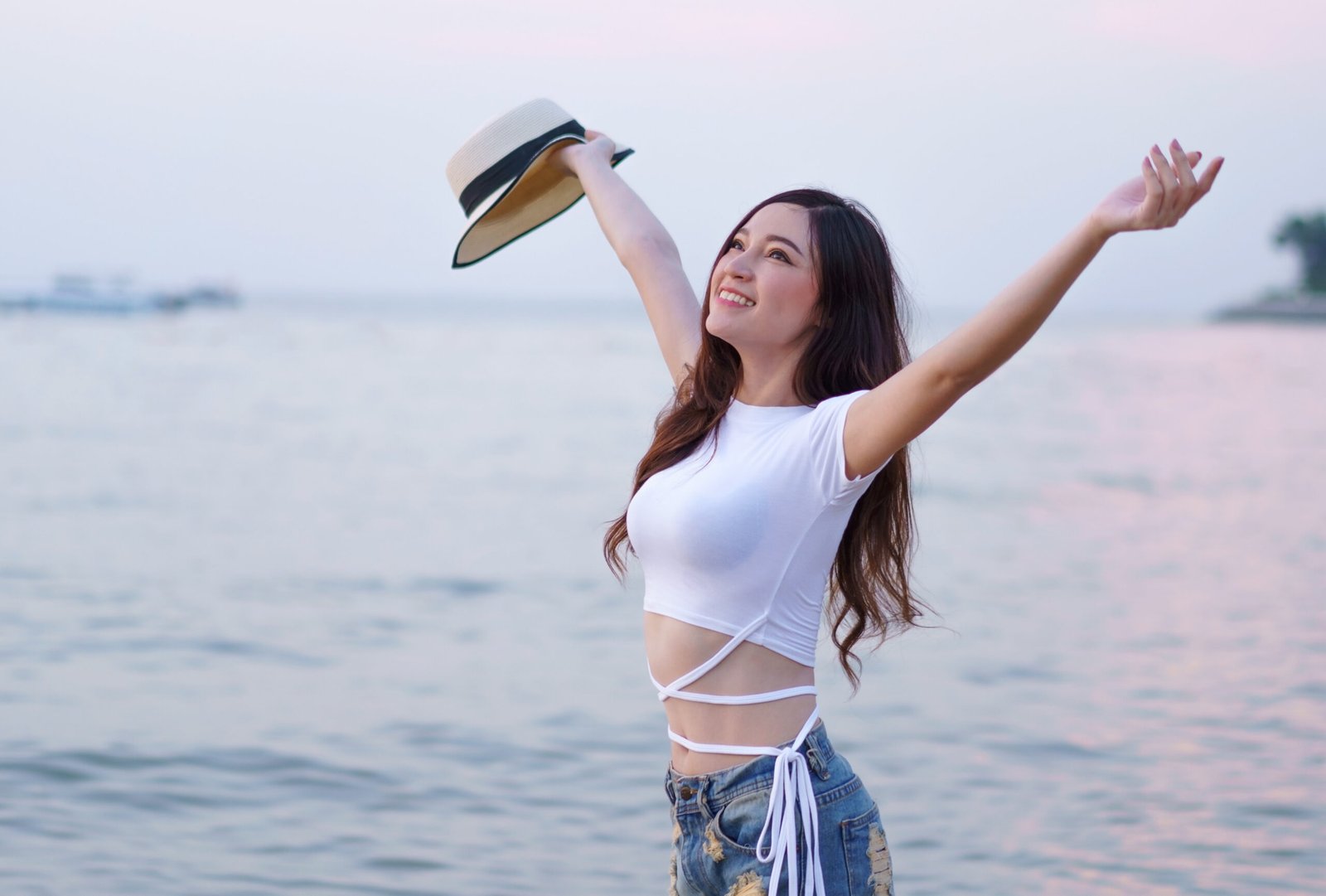cappelli per il mare : borsalino tenuto in mano da una ragazza felice davanti al mare al tramonto
