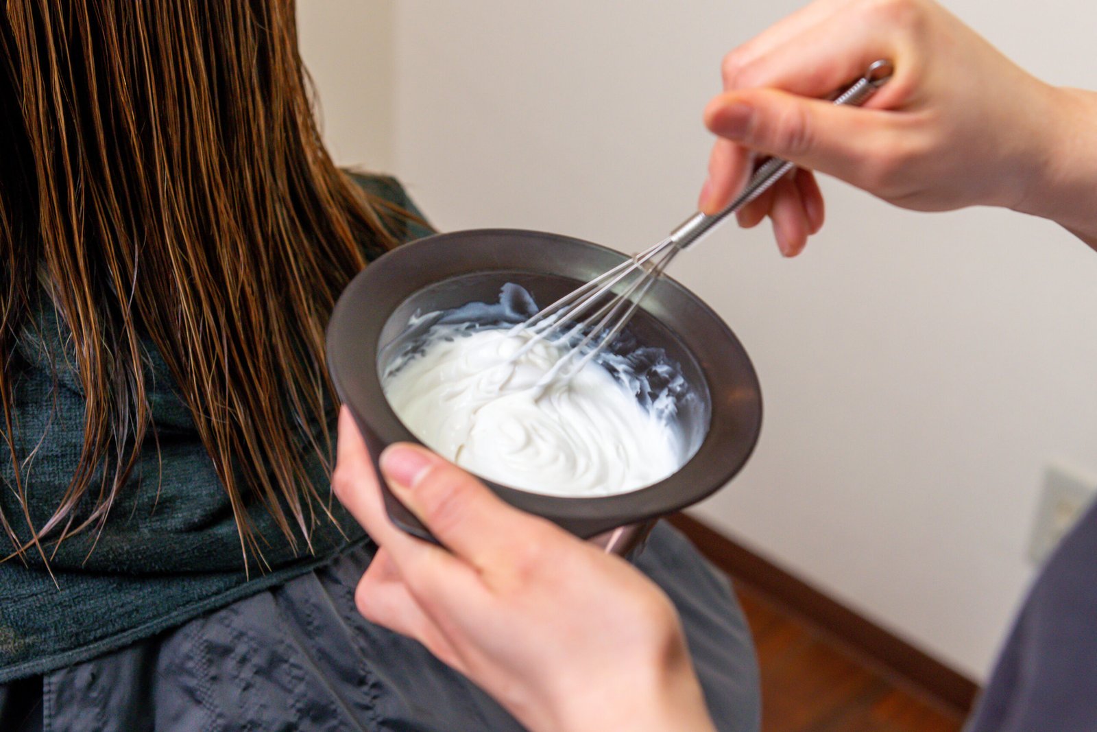 tema : Come usare Casting Crème Gloss - foto in primo piano della ciotola in cui si sta mescolando il prodotto e donna di spalle pronta alla applicazione della tinta