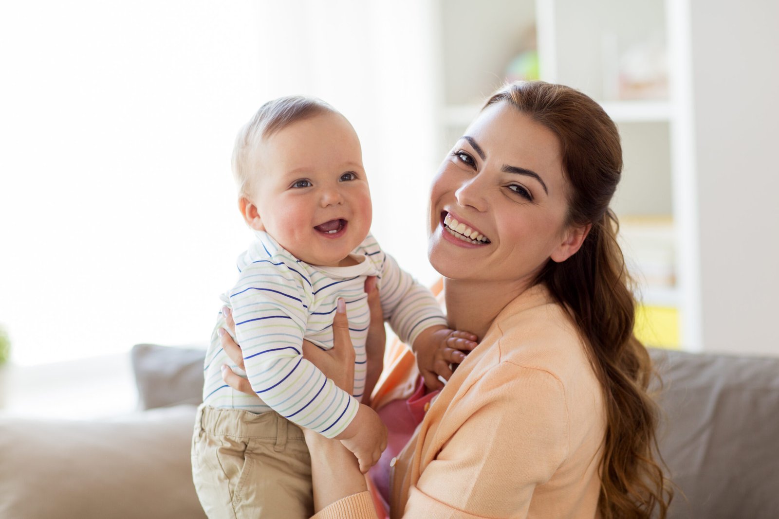 Concetto di famiglia, figlio e maternità: una giovane madre felice e sorridente con un bambino piccolo a casa.