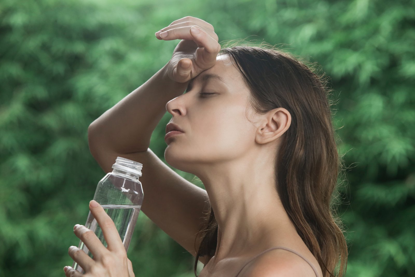 concetto di integrazione e di potassio e magnesio quando prenderli. giovane donna accaldata in estate beve di una bottiglia e si asciuga la fronte 